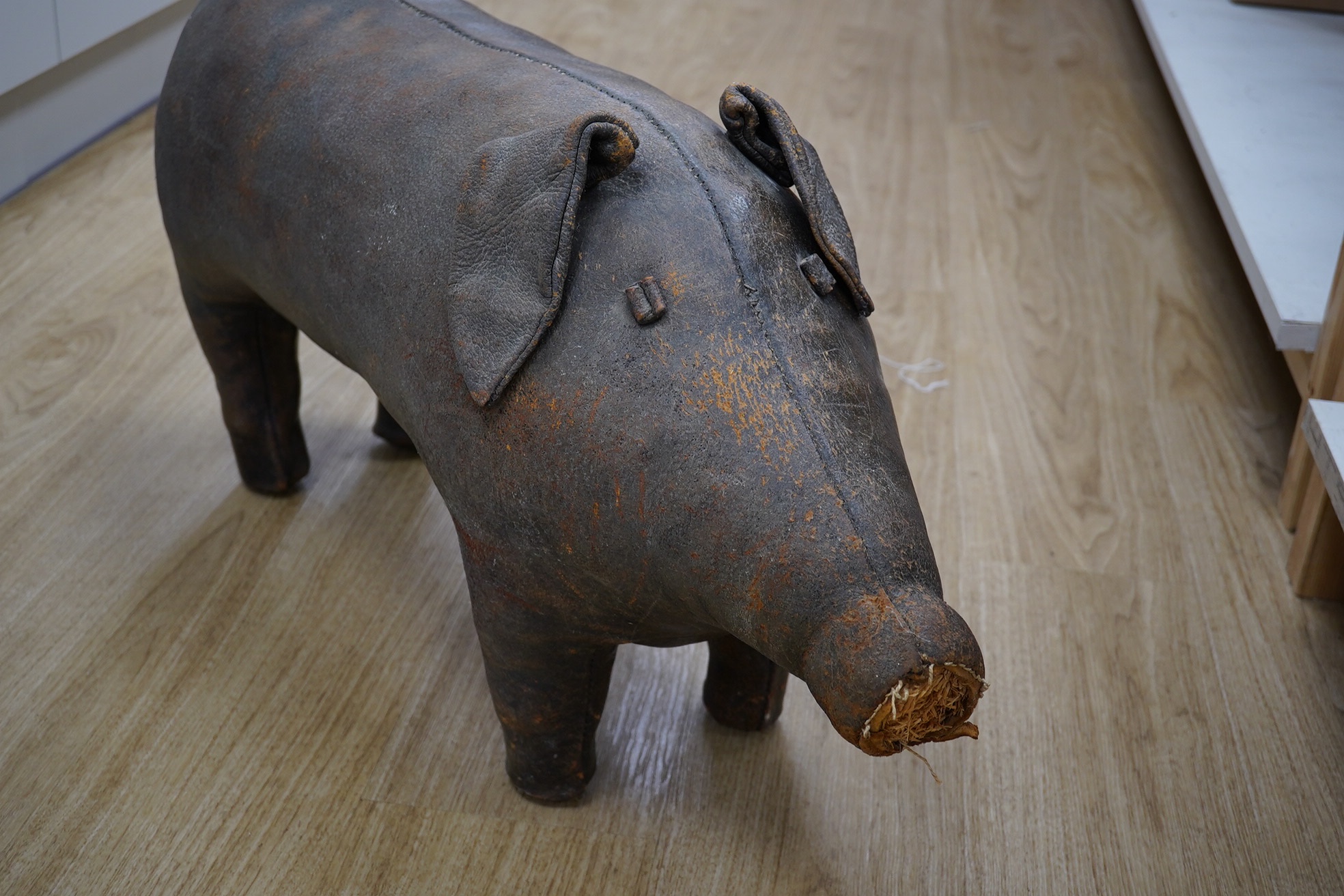 A Liberty brown leather pig foot stool, 90cm long. Condition - the end of the tail and snout are missing and generally leather scuffed